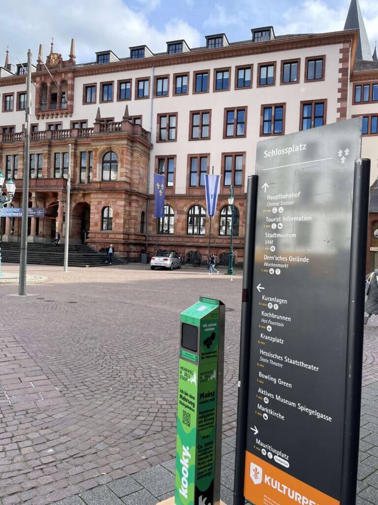 Eine kooky Rücknahmebox an einer Infotafel am Schlossplatz in Wiesbaden. Aufnahme im Rahmen des Projekts Mehrweg Modell Stadt.